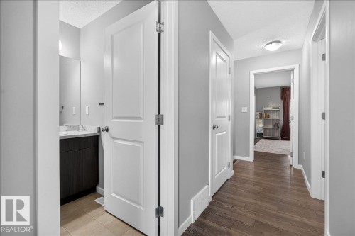 Hallway featuring wood-finish flooring, white paneled doors, and light gray wall paint - 3043 Keswick Way Sw, Edmonton, AB - Indoor Photo Showing Other Room