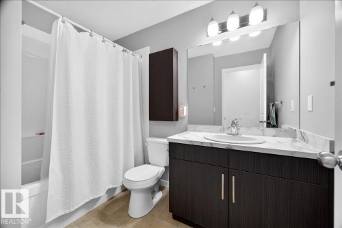 Bathroom featuring a white tub and shower combination, dark wood-finish vanity with a white countertop, oval undermount sink, and a wall-mounted medicine cabinet - 3043 Keswick Way Sw, Edmonton, AB - Indoor Photo Showing Bathroom