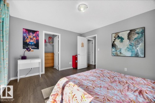 Spacious room featuring wood-finish flooring, light grey painted walls, a built-in closet with a wooden dresser, and a ceiling-mounted light fixture - 3043 Keswick Way Sw, Edmonton, AB - Indoor Photo Showing Bedroom
