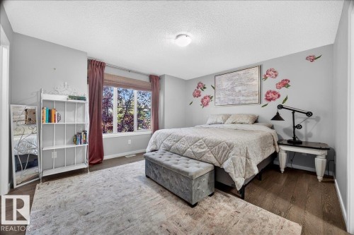 Bedroom featuring wood-finish flooring, light grey painted walls, and a large window with privacy blinds - 3043 Keswick Way Sw, Edmonton, AB - Indoor Photo Showing Bedroom