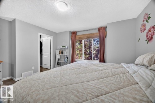 Bedroom featuring a large window, light gray walls, white trim, and wood-finish flooring - 3043 Keswick Way Sw, Edmonton, AB - Indoor Photo Showing Bedroom