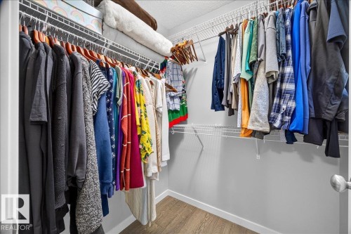 Expansive closet featuring wire shelving, multiple hanging rods, light gray walls, white trim, and wood-finish flooring - 3043 Keswick Way Sw, Edmonton, AB - Indoor With Storage