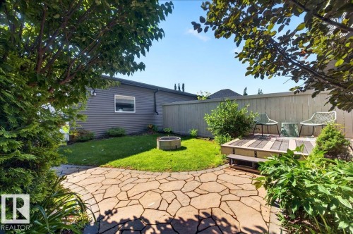Stone paver patio leading to a tiered wood-finish deck with a surrounding lawn - 3043 Keswick Way Sw, Edmonton, AB - Outdoor