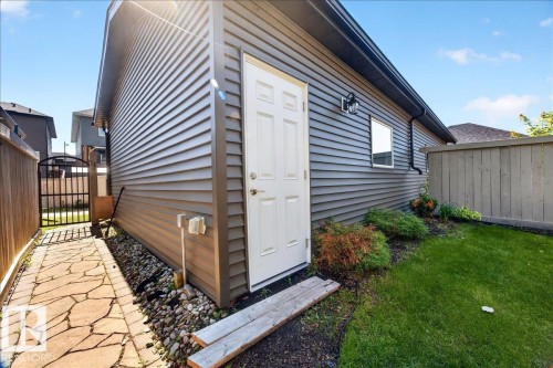 Detached garage with horizontal siding, a white service door, and an exterior light fixture - 3043 Keswick Way Sw, Edmonton, AB - Outdoor With Exterior