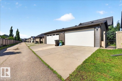 Rear-facing garage with two white doors, gray horizontal siding, and dark trim - 3043 Keswick Way Sw, Edmonton, AB - Outdoor