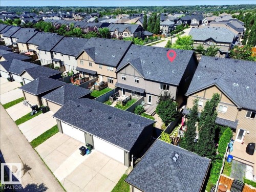 Townhome featuring a dark shingle roof, light-toned siding, and a rear deck - 3043 Keswick Way Sw, Edmonton, AB - Outdoor