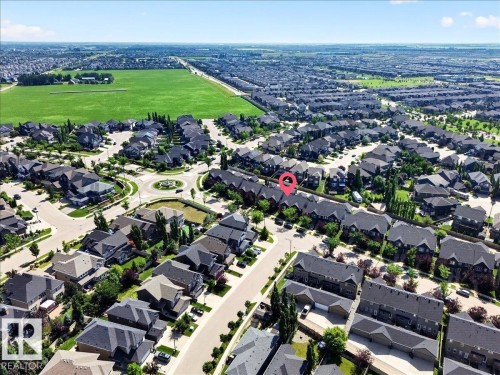 Residential community featuring a variety of detached homes and townhomes, surrounded by landscaped streets and a central roundabout with decorative planting - 3043 Keswick Way Sw, Edmonton, AB - Outdoor With View