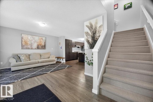 Carpeted staircase with white railings, hardwood-finish flooring, recessed lighting, and light gray wall finishes - 3043 Keswick Way Sw, Edmonton, AB - Indoor