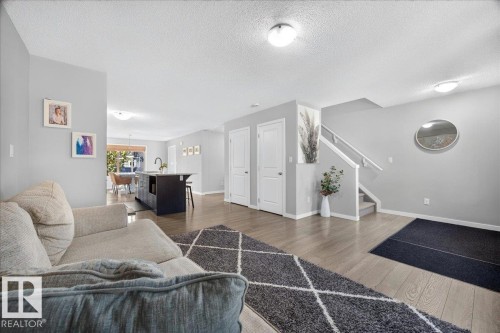 Open-concept living area with light-colored walls and wood-finish flooring - 3043 Keswick Way Sw, Edmonton, AB - Indoor Photo Showing Living Room