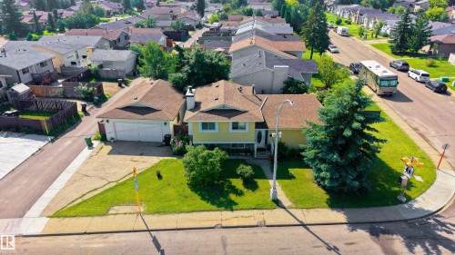 Corner lot property featuring a light yellow exterior with brown roofing - 611 Kirkness Road Nw, Edmonton, AB - Outdoor