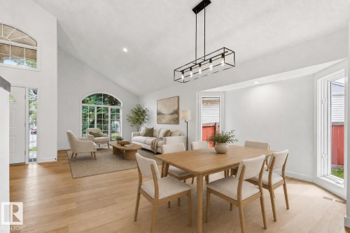 Open-concept living area featuring vaulted ceilings, wood-finish flooring, and multiple arched windows - 140 Healy Road Nw, Edmonton, AB - Indoor Photo Showing Dining Room