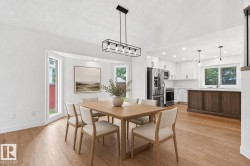 Open-concept dining area featuring light wood-finish flooring and a contemporary linear chandelier - 