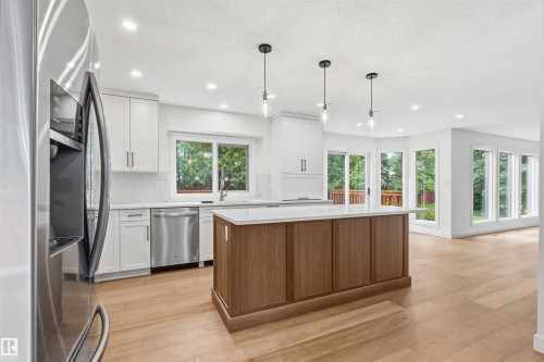 Modern kitchen featuring a wood-finish island with a light-toned countertop, white cabinetry, and stainless steel appliances - 140 Healy Road Nw, Edmonton, AB - Indoor Photo Showing Kitchen With Upgraded Kitchen