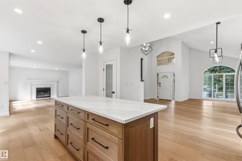 Central kitchen island with a stone-finish countertop and wood-finish cabinetry - 140 Healy Road Nw, Edmonton, AB - Indoor With Fireplace