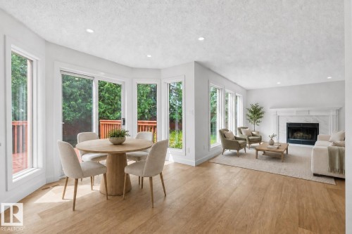 Open-concept living space featuring wood-finish flooring, recessed lighting, and a white marble-surround fireplace - 140 Healy Road Nw, Edmonton, AB - Indoor Photo Showing Other Room With Fireplace