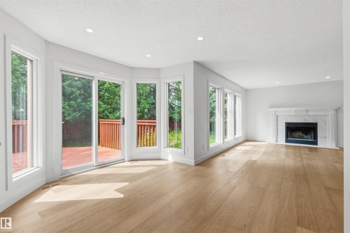 Spacious living area featuring light wood-finish flooring, a white mantel fireplace with a stone surround, and recessed lighting - 140 Healy Road Nw, Edmonton, AB - Indoor Photo Showing Living Room With Fireplace