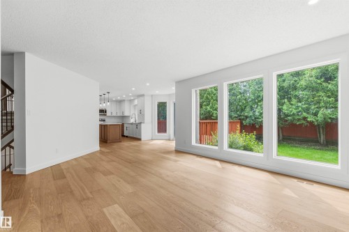 Expansive living area featuring light wood-finish flooring and a wall of three large windows - 140 Healy Road Nw, Edmonton, AB - Indoor