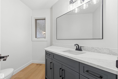 Bathroom vanity featuring a quartz countertop with an integrated sink, matte black faucet, and dark gray cabinetry - 140 Healy Road Nw, Edmonton, AB - Indoor Photo Showing Bathroom