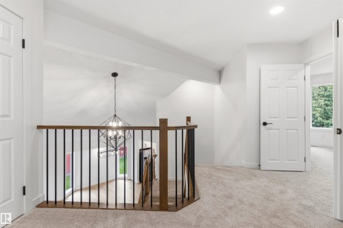 Upper landing featuring neutral carpet flooring, white walls, and a modern geometric chandelier - 140 Healy Road Nw, Edmonton, AB - Indoor Photo Showing Other Room