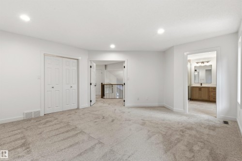 Spacious carpeted room featuring recessed lighting, a bi-fold closet, and access to a full bathroom with a wood-finish vanity - 140 Healy Road Nw, Edmonton, AB - Indoor Photo Showing Other Room