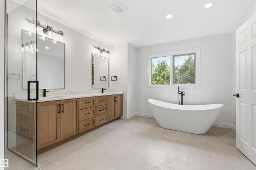 Contemporary bathroom featuring a freestanding tub, a dual vanity with wood-finish cabinetry, a glass-enclosed shower, and light-toned tile flooring - 140 Healy Road Nw, Edmonton, AB - Indoor Photo Showing Bathroom