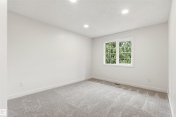 Bedroom with light gray carpet, white walls, recessed ceiling lighting, and a white-framed window - 