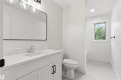 Bathroom featuring a white vanity with a quartz countertop, an undermount sink, and matte black hardware - 