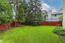 Expansive green lawn with a perimeter red privacy fence - 