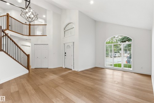 Grand entry featuring a two-story ceiling, wood-finish flooring, and a contemporary chandelier - 140 Healy Road Nw, Edmonton, AB - Indoor Photo Showing Other Room