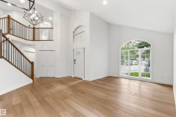 Grand entry featuring a two-story ceiling, wood-finish flooring, and a contemporary chandelier - 