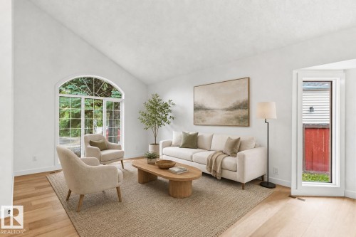 Vaulted ceiling living space featuring an arched picture window, wood-finish flooring, and crisp white walls - 140 Healy Road Nw, Edmonton, AB - Indoor Photo Showing Living Room