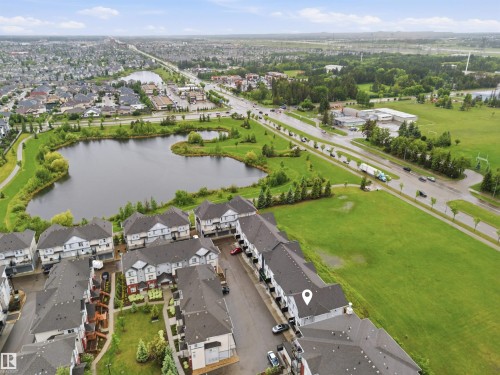 Aerial perspective showcasing a residential development with structured streetscapes - #64 655 Watt Bv Sw, Edmonton, AB - Outdoor With Body Of Water With View
