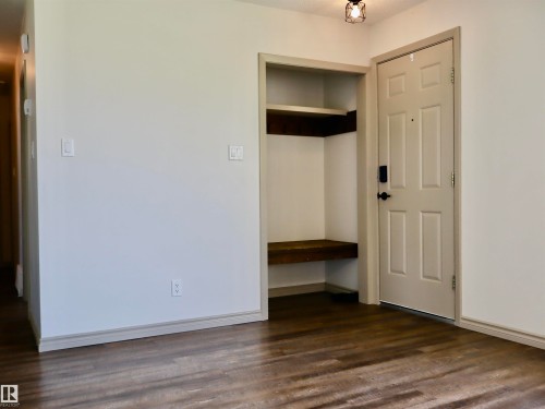 Entryway with wood-finish flooring, built-in shelving, and a panel door with black hardware - 4306 - 55 Ave, Barrhead, AB - Indoor Photo Showing Other Room