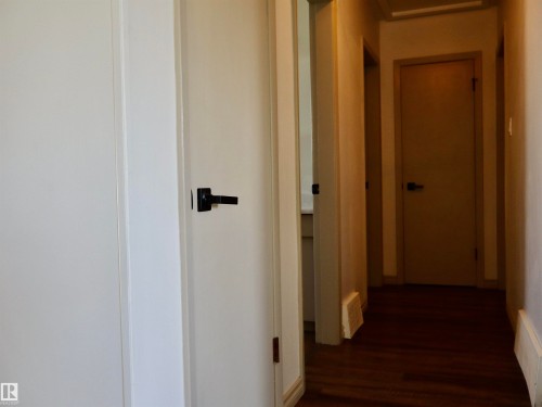 Hallway featuring wood-finish flooring, white paneled doors, and matte black door hardware - 4306 - 55 Ave, Barrhead, AB - Indoor Photo Showing Other Room
