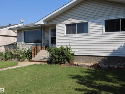 Front exterior featuring light-colored horizontal siding and a gabled roofline - 