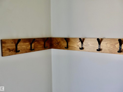 Corner-mounted wooden coat rack with multiple black metal hooks - 4306 - 55 Ave, Barrhead, AB - Indoor