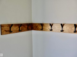 Corner-mounted wooden coat rack with multiple black metal hooks - 