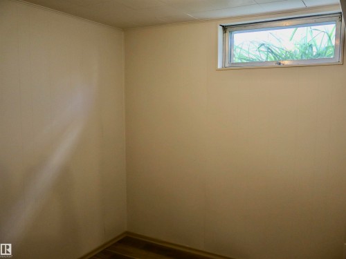 Interior space featuring a horizontal window, wood-finish flooring, and light-toned wall paneling - 4306 - 55 Ave, Barrhead, AB - Indoor Photo Showing Other Room