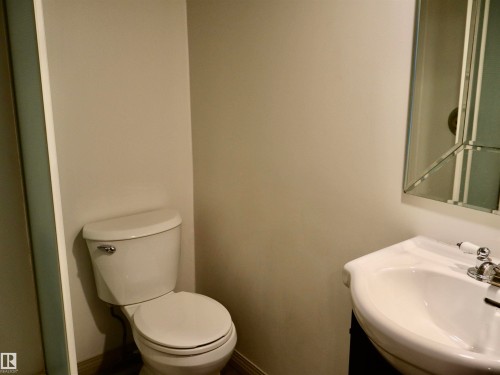 Powder room featuring a pedestal sink with chrome faucet, a beveled mirror, and light neutral wall tones - 4306 - 55 Ave, Barrhead, AB - Indoor Photo Showing Bathroom