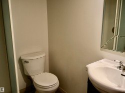 Powder room featuring a pedestal sink with chrome faucet, a beveled mirror, and light neutral wall tones - 