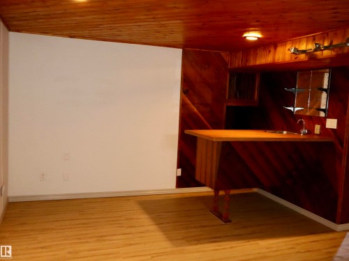 Wood-paneled accent wall with built-in bar featuring a sink and wood-finish countertop - 4306 - 55 Ave, Barrhead, AB - Indoor Photo Showing Other Room