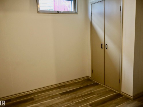 Recessed storage cabinetry with black hardware, wood-finish flooring, and white baseboards - 4306 - 55 Ave, Barrhead, AB - Indoor Photo Showing Other Room