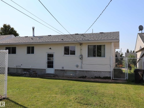 Rear exterior with white vinyl siding, a gray shingle roof, and a green lawn - 4306 - 55 Ave, Barrhead, AB - Outdoor With Exterior