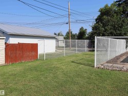 Expansive green lawn featuring white chain-link fencing and a wood privacy fence - 