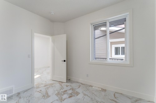 Spacious interior room featuring white walls, white baseboards, and elegant marble-look tile flooring - 4723 17 Avenue Sw, Edmonton, AB - Indoor