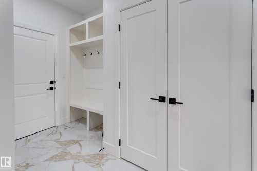 Built-in mudroom bench with upper cubbies and coat hooks, complemented by white panel doors with matte black hardware - 4723 17 Avenue Sw, Edmonton, AB - Indoor Photo Showing Other Room