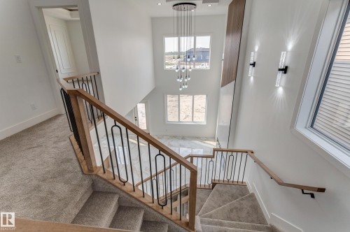 Multi-level staircase with light wood-finish handrails and black metal balusters - 4723 17 Avenue Sw, Edmonton, AB - Indoor Photo Showing Other Room