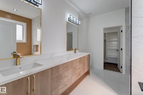 Double vanity featuring wood-finish cabinetry, white countertops, dual undermount sinks, and gold-finish fixtures - 4723 17 Avenue Sw, Edmonton, AB - Indoor Photo Showing Bathroom