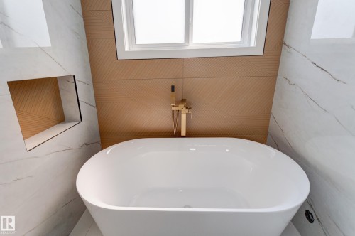 Freestanding oval soaking tub with a wall-mounted gold-tone faucet - 4723 17 Avenue Sw, Edmonton, AB - Indoor Photo Showing Bathroom