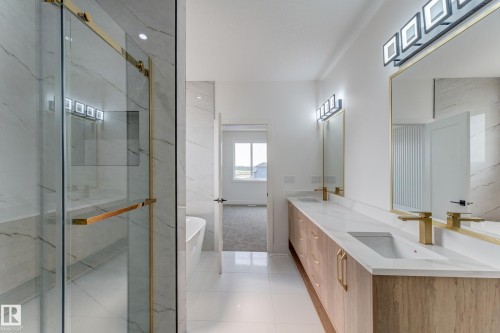 Bathroom featuring a frameless glass shower with gold-tone hardware, a freestanding bathtub, a double vanity with light wood-finish cabinetry, integrated sinks, and gold-tone fixtures - 4723 17 Avenue Sw, Edmonton, AB - Indoor Photo Showing Bathroom